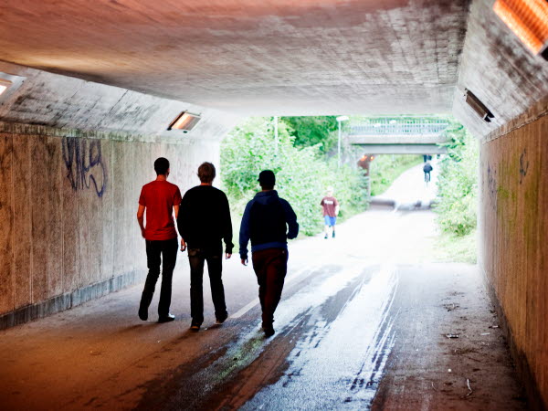 Tre unga killar går i gångtunnel