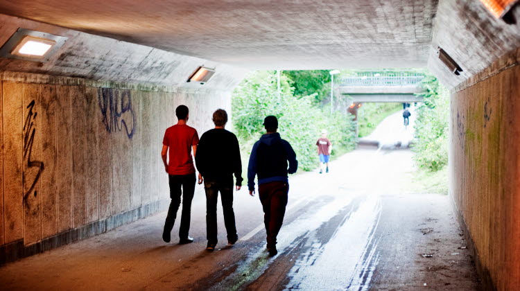 Tre unga killar går i gångtunnel